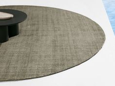 a round rug next to a pool with a black and white table in the middle