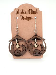 a pair of wooden earrings with an elephant and star on the front, sitting next to a sign that says wilder mind designs