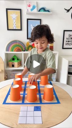 a young child playing with orange cups on a table