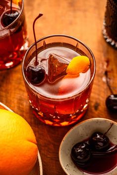 two glasses filled with different kinds of drinks on top of a wooden table next to an orange