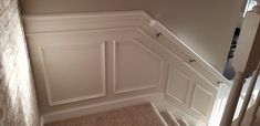 an empty room with white paneling and carpeted stairs leading up to the second floor