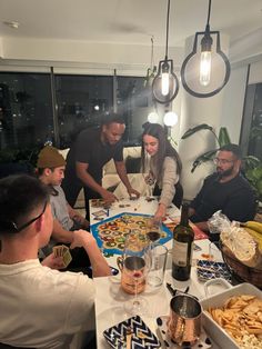 a group of people sitting around a table with food and wine in front of them