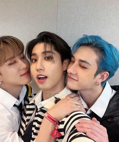 three young men with blue hair hugging each other