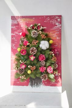 a christmas tree made out of pine cones and other holiday decorations on a pink background