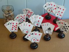 several playing cards are sitting on a table next to some jars and glass containers with coins in them