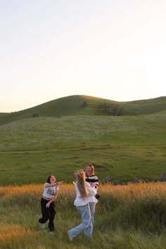 three people are running in the grass with one holding onto another person's shoulder