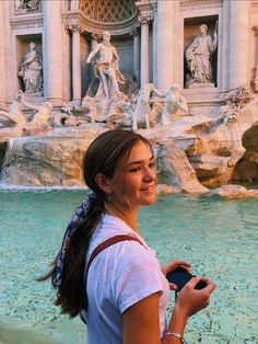 a woman standing in front of a water fountain