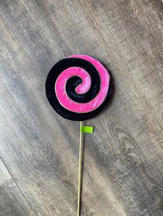 a pink and black lollipop sitting on top of a wooden floor