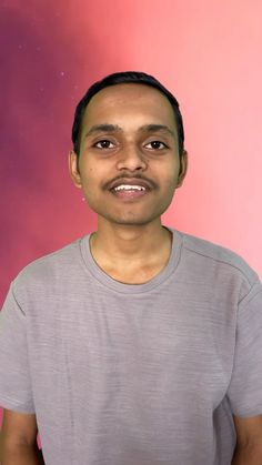 a man standing in front of a pink and purple background with his eyes wide open