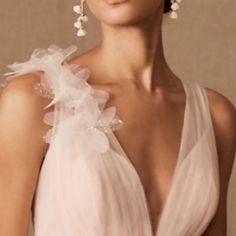 a woman in a white dress with large earrings on her head and wearing a flowered necklace