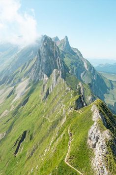 the view from the top of a mountain looking down on a path in the grass