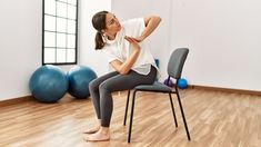 a woman sitting on top of a chair in a room with exercise balls behind her