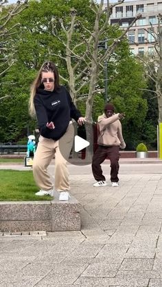 two people are doing tricks in the park while one person is holding a skateboard