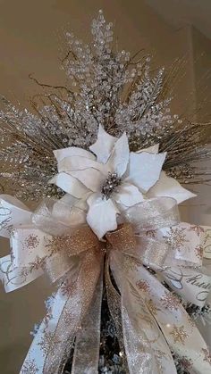 a christmas tree decorated with white and silver ribbons, poinsettis and snowflakes