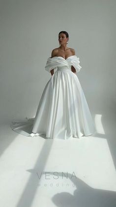 a woman in a white wedding dress posing for the camera with her hands on her hips