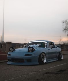 a blue car parked on the side of a road next to a tall pole in the background