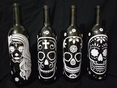 three wine bottles with painted skulls on them