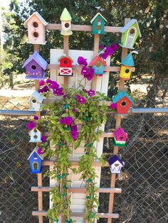 a wooden fence with bird houses and flowers on it