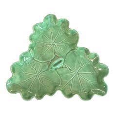 a green ceramic dish with leaves on it's sides and one leaf in the middle