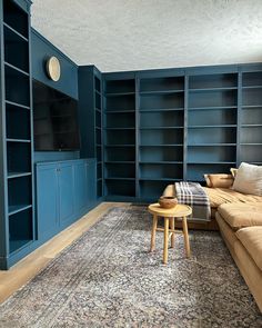 a living room with blue bookcases and a large rug