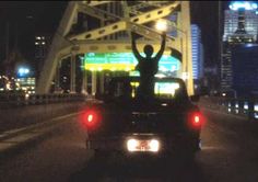 a man standing on the back of a truck in the middle of a city at night