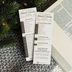 two bookmarks sitting next to an open book on top of a knitted blanket