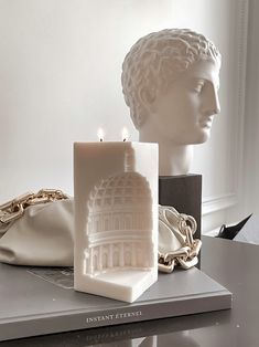 a white statue sitting on top of a table next to a bag and candle holder