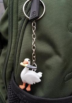 a duck keychain is attached to a green backpack with a black metal ring