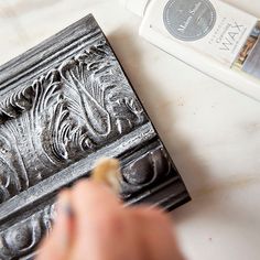 a person is using a pen to draw on a piece of metal with silver paint