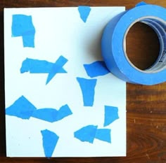 a roll of blue tape sitting on top of a piece of paper next to a wooden table