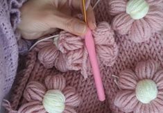 someone crocheting flowers on a pink sweater