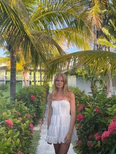 a woman standing in front of some palm trees