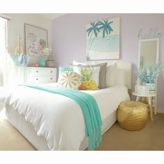 a bedroom decorated in pastel colors with palm trees on the wall and pictures above the bed