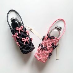 two crocheted shoes are next to each other on a white surface, one has a bottle and the other has a tag