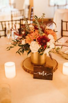 a centerpiece with flowers and candles on a table