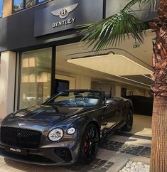 a black convertible car parked in front of a bentley dealership with palm trees on the sidewalk