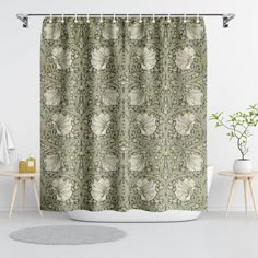 a green shower curtain with white flowers and leaves on it in front of a bathtub