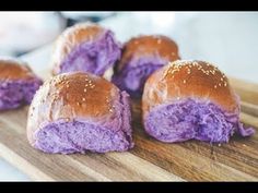 four rolls covered in purple food sitting on top of a wooden cutting board