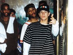 a group of young men standing next to each other in front of a door with one pointing at the camera