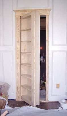 an empty room with white walls and wooden shelves on the wall next to a bed