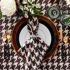 a place setting with black and white napkins, silverware, and flowers on the table