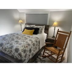 a bedroom with a bed, rocking chair and two lamps on either side of the bed