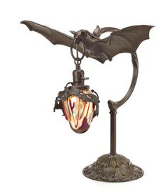 an old fashioned lamp with a bat on it's arm and wings attached to the light