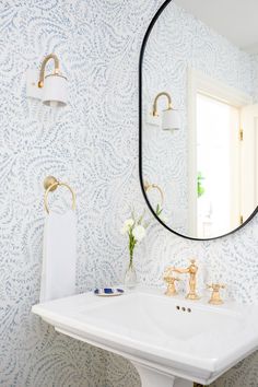 a white sink sitting under a bathroom mirror next to a wall mounted faucet