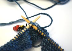 two crocheted pieces of blue yarn are next to a pair of knitting needles