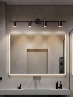 a bathroom with a sink, mirror and lights on the wall above it's counter