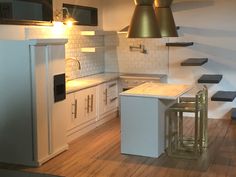 a kitchen with white cabinets and wooden floors, lights above the stove top and refrigerator