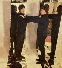 two men standing in front of a mirror with their arms around each other's shoulders