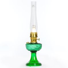 a green glass table lamp with a light bulb on it's base and a gold plated top