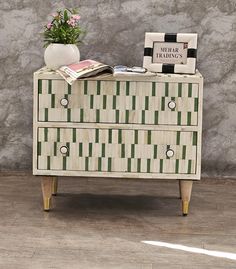 a white and green chest of drawers sitting on top of a hard wood floor next to a wall